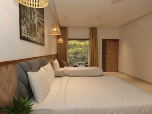 Habitación de hotel moderna con una cama grande, vistas a zonas verdes y un balcón.