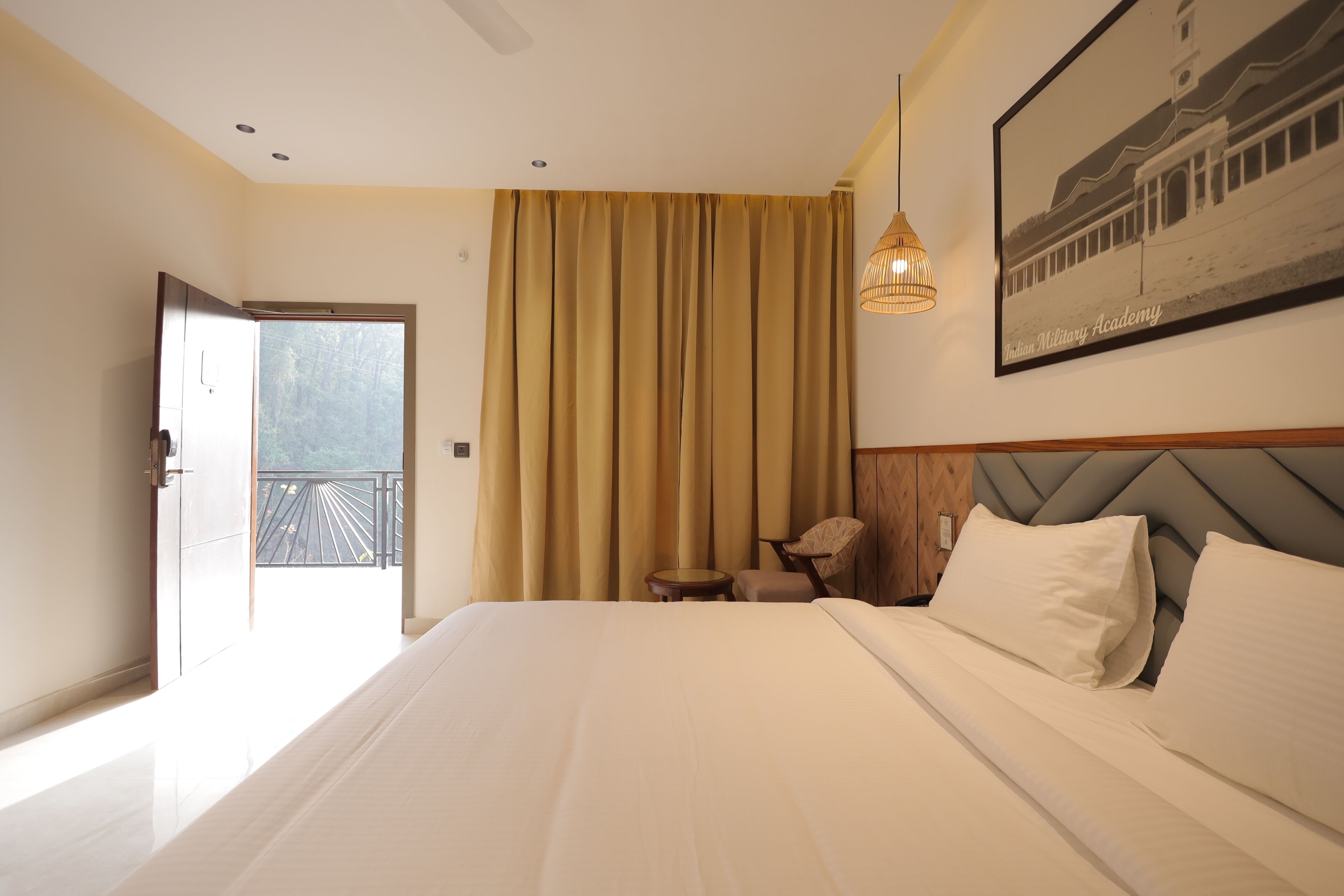 Een hotelkamer met een groot bed, een kleintje tafeltje, een stoel en een balkon met een hekwerk.