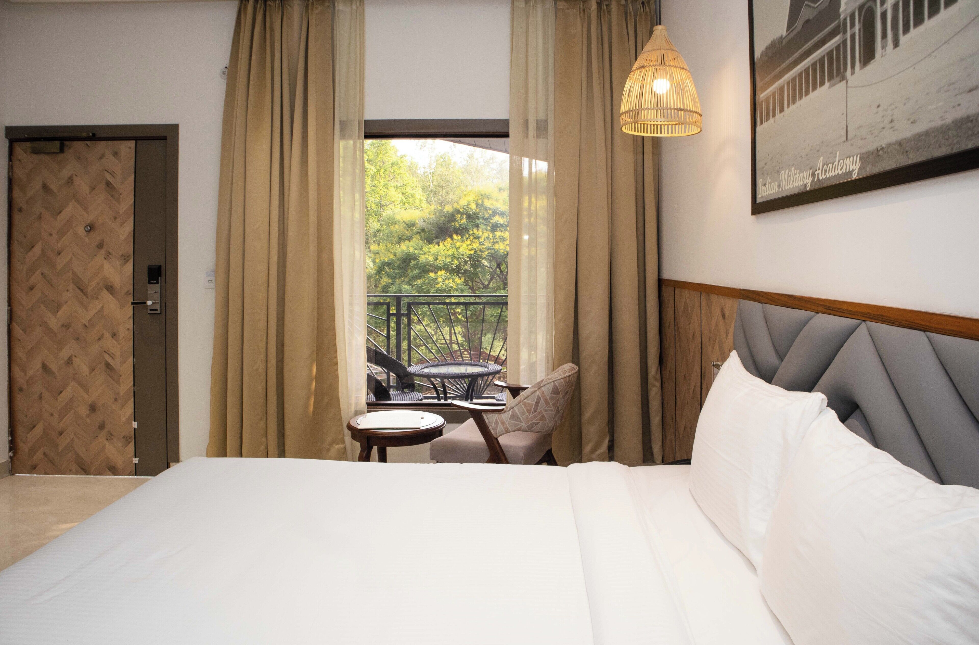 Une chambre d’hôtel comprenant un lit, une petite table, deux chaises, un balcon avec une balustrade et un luminaire suspendu.