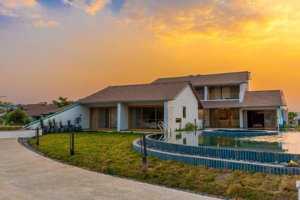 Una casa moderna con piscina, ventanas amplias y un césped bien cuidado.