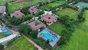 An aerial view of a residential area with houses, a swimming pool, and a tennis court.