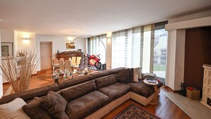 Ein modernes Wohnzimmer mit einer großen Eckcouch, einem Esstisch und einem Motorrad im Hintergrund.