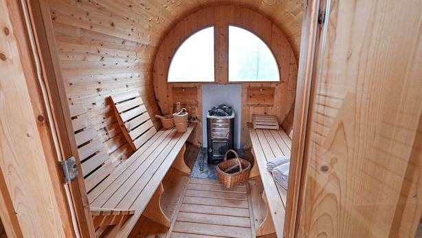 Eine Holzsauna mit Bänken, einem Kamin und einem großen Bogenfenster.