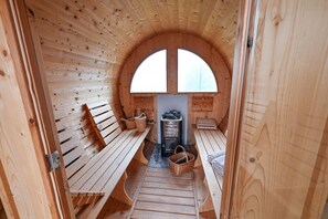 A wooden sauna with benches, a fireplace, and a large arched window. - Host Monti del Sole (Santa Giustina)