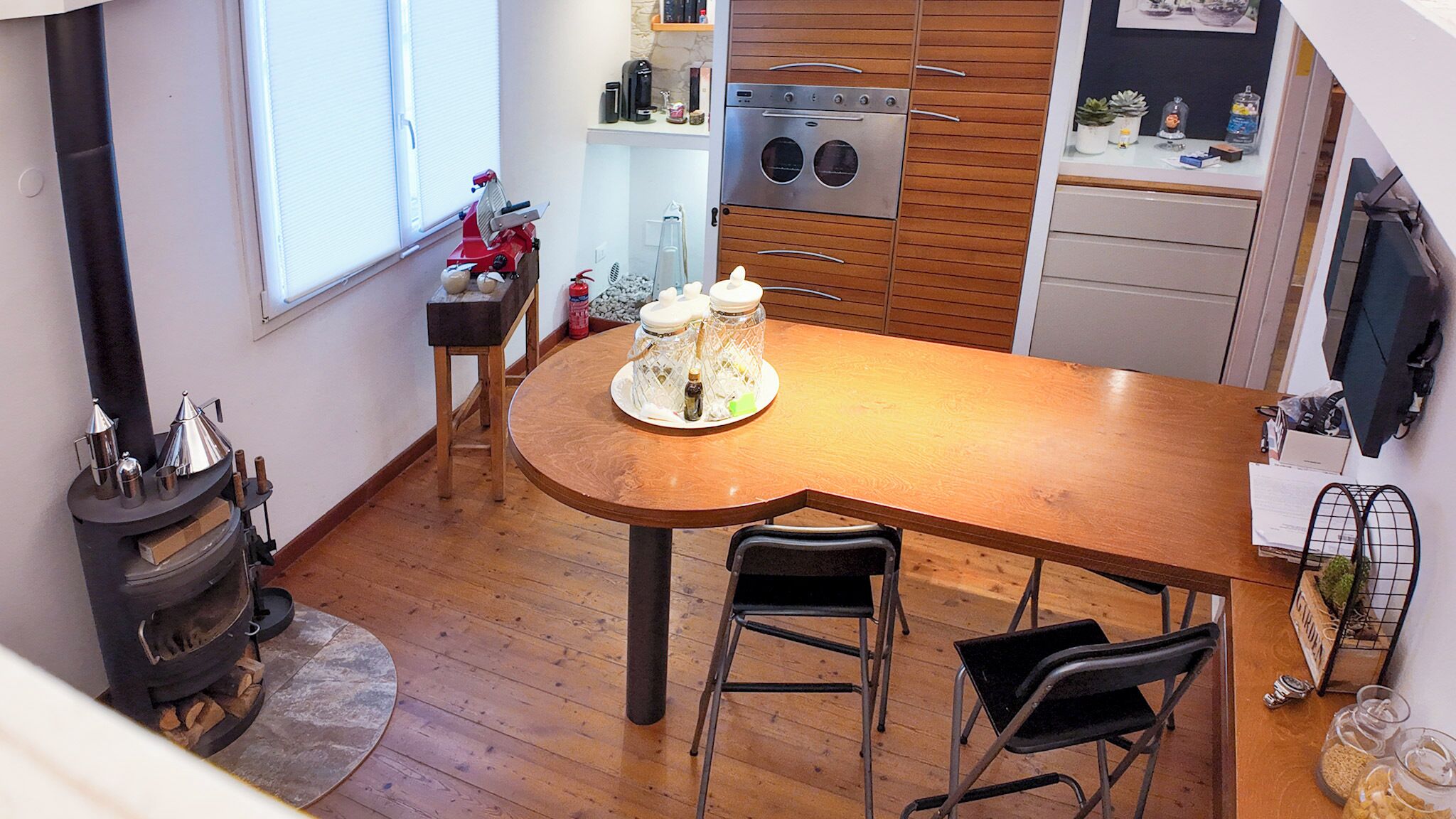 Una cocina compacta con una mesa de madera, dos sillas, horno empotrado y estufa.