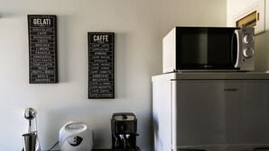 Eine Küche mit Kaffeemaschine, Mikrowelle und zwei schwarzen Schildern, die Gelato- und Kaffeeauswahl zeigen.