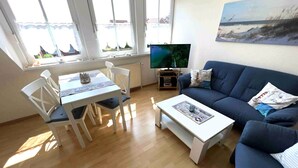 A living room with a dining table, chairs, a sofa, a coffee table, and a TV.
