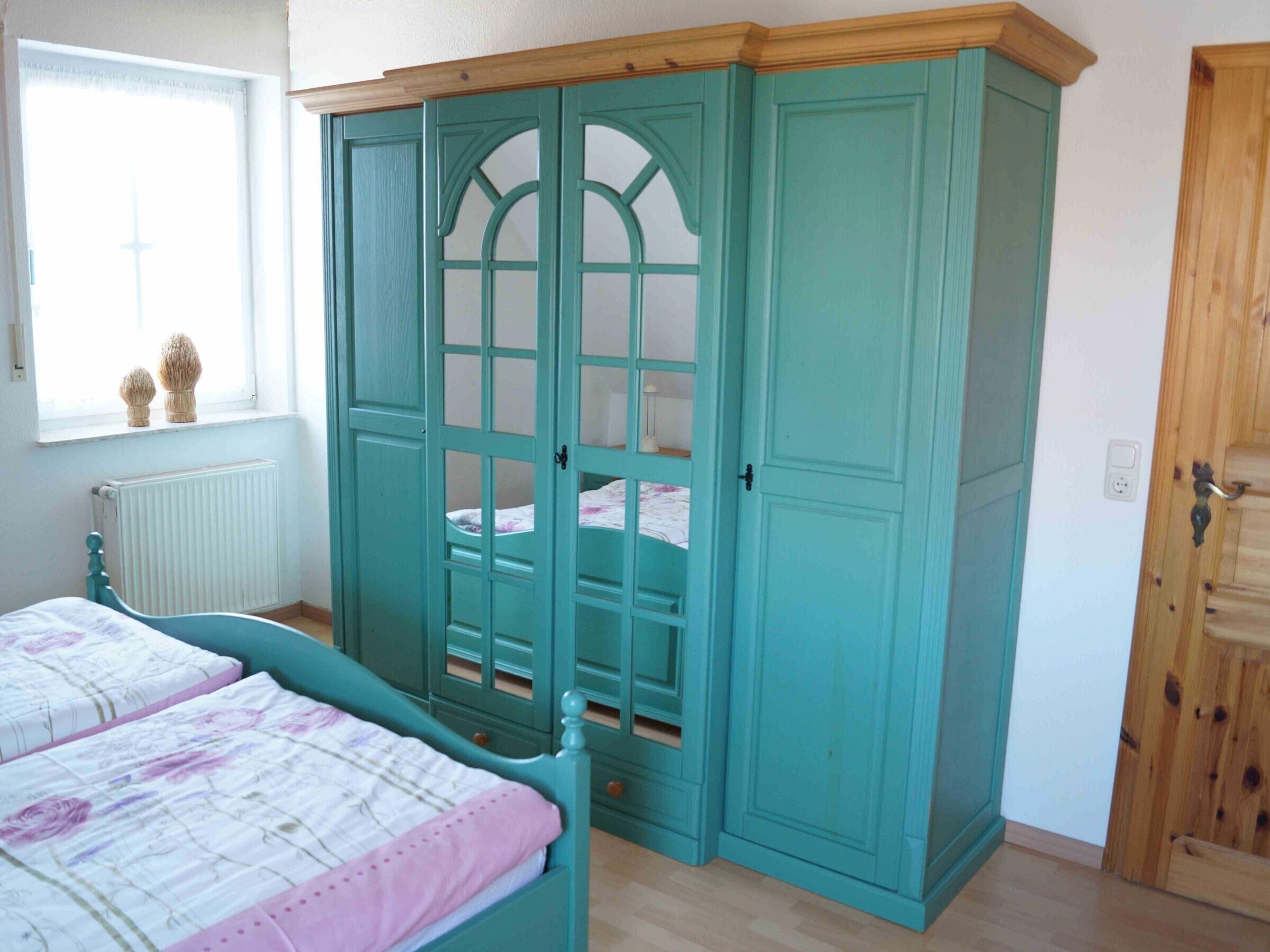 A bedroom with a bed, a wardrobe, and a window.