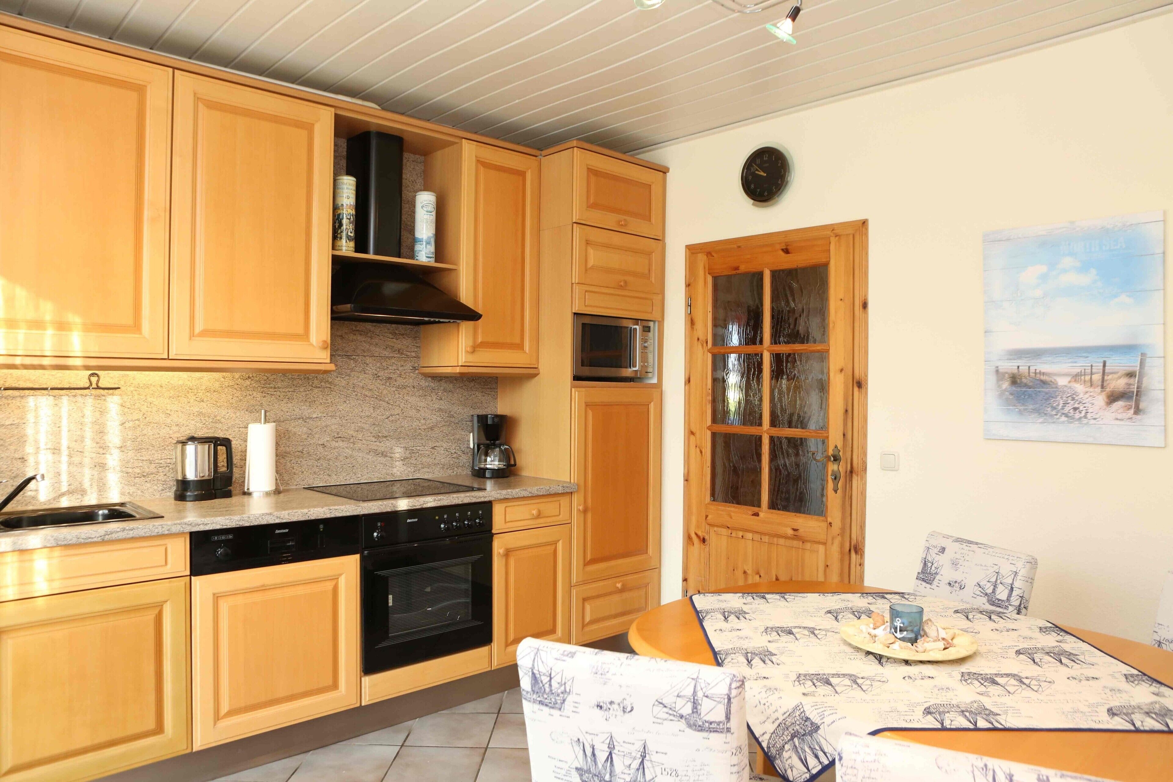 A kitchen with wooden cabinets, a microwave, a stove, and a dining area with a table and chairs.