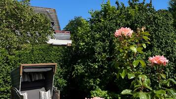 Une terrasse avec un barbecue, des sièges d’extérieur et un rosier.