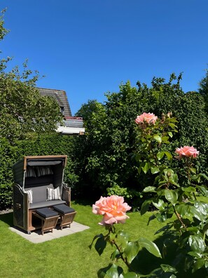 En terrasse med grill, udendørs møbler og en rosenbusk.