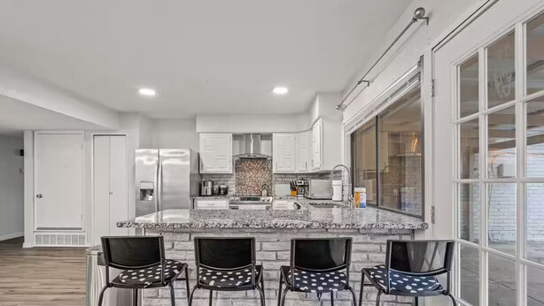 A modern kitchen with a marble island, stainless steel appliances, and a large window. - 4BR Home w/ Arcade, Foosball & Desks - Carrollton (Carrollton)
