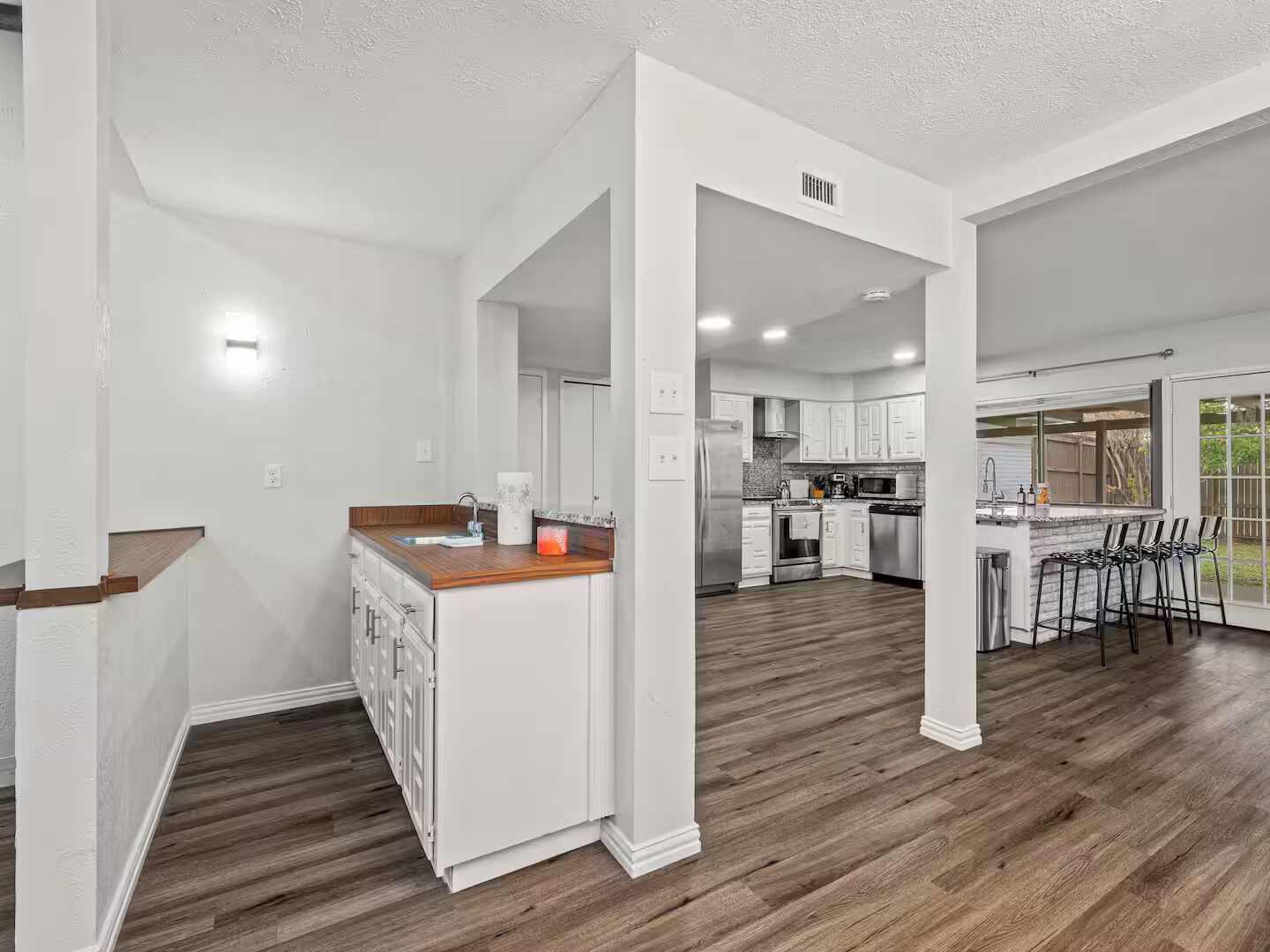 A modern kitchen with white cabinetry, a wooden countertop, and a built-in island.
