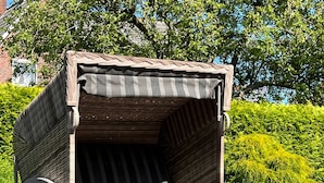 Un'area relax all'aperto riparata, con una panca imbottita e due poggiapiedi abbinati.
