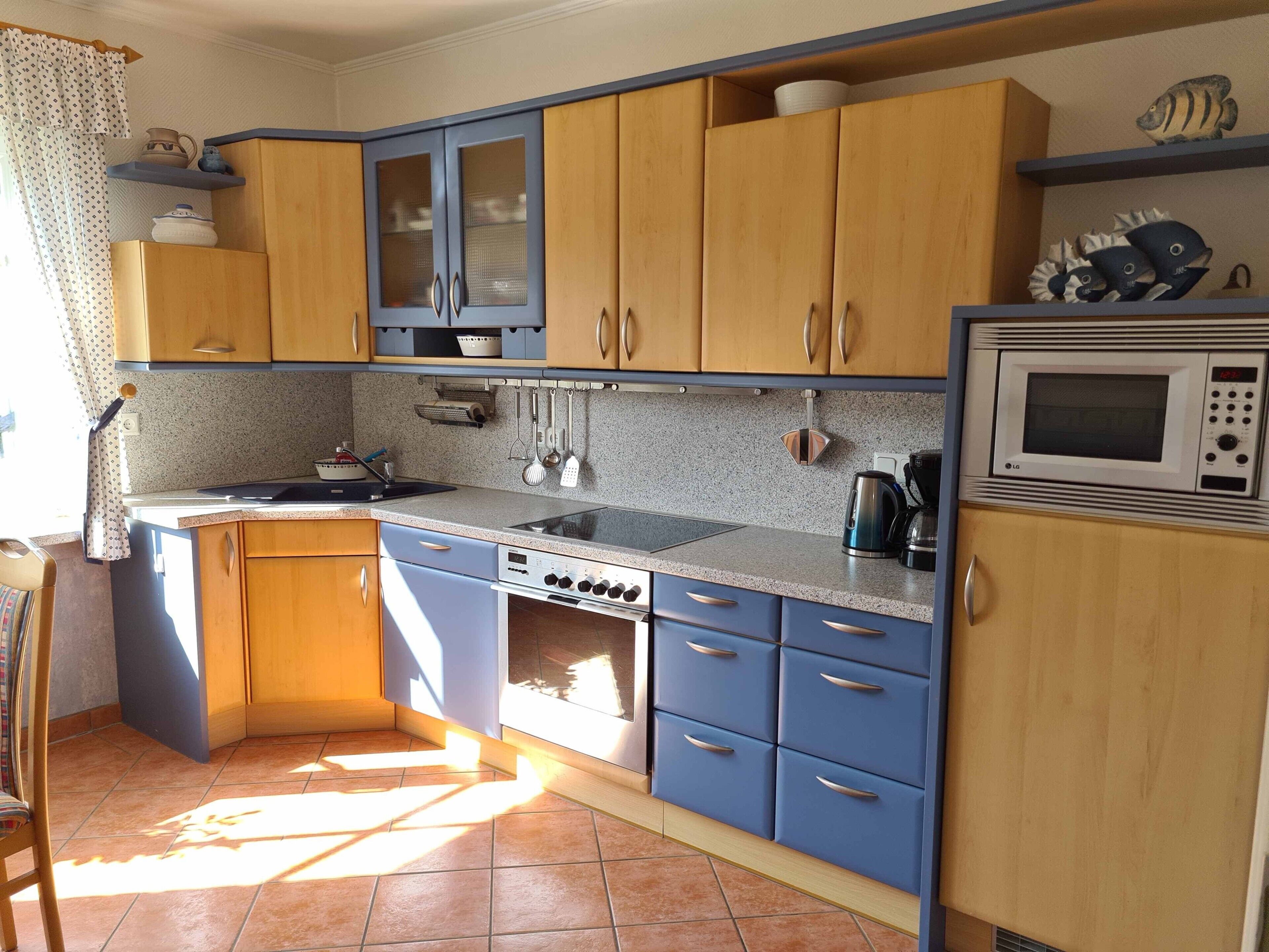 A compact kitchen with a stove, microwave, and various utensils.