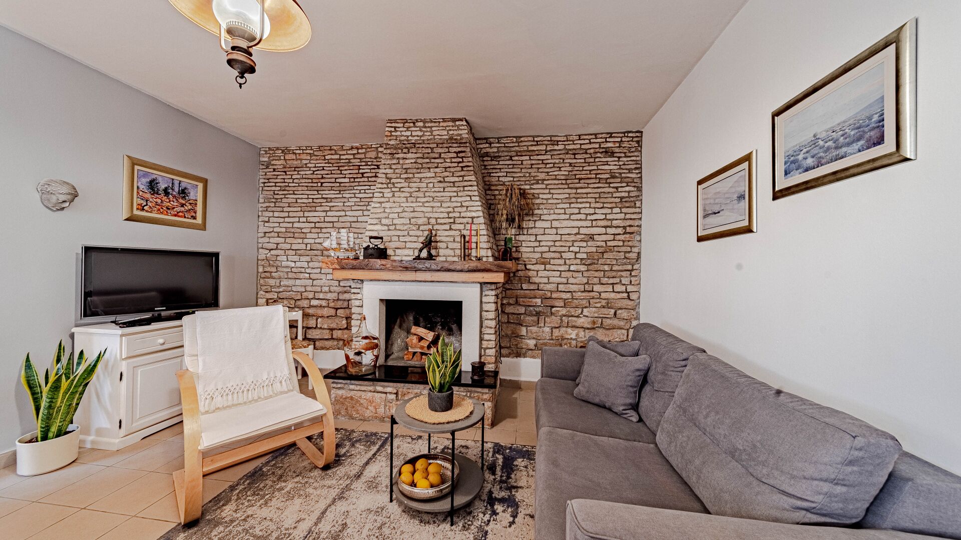 A living room with a fireplace, a sofa, a TV, and a stone wall.