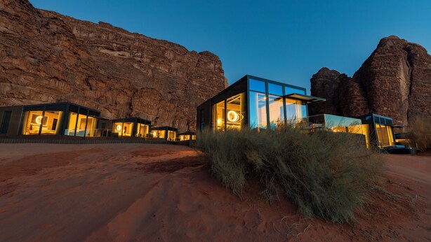Un edificio moderno con amplios ventanales y el desierto al fondo.