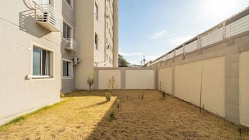 Een binnenplaats met een droog gazon, een kleine boom en een gebouw met balkons en ramen.