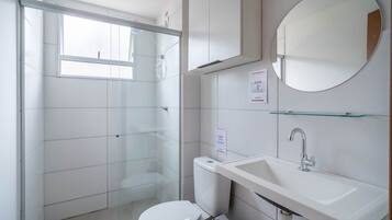 Uma casa de banho moderna com sanita, lavatório e cabine de duche em vidro.