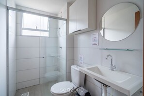 Ein modernes Badezimmer mit Toilette, Waschbecken und Duschkabine aus Glas.