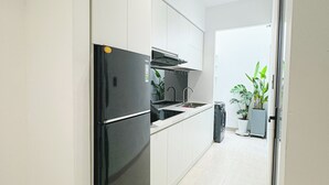 Une cuisine moderne avec des armoires blanches, un réfrigérateur noir et un four encastré.