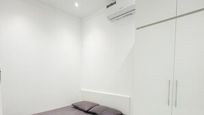 Une chambre à coucher comprenant un lit, une armoire et un appareil de climatisation.
