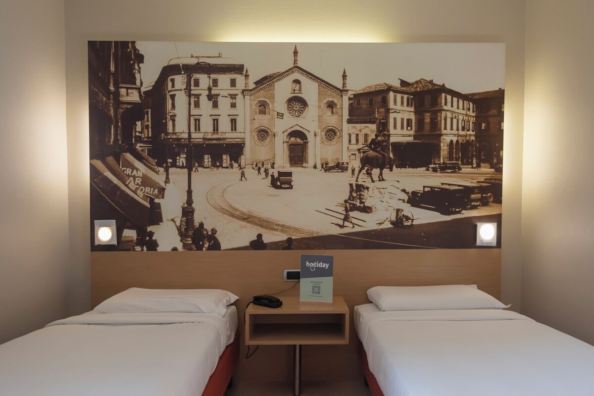 A hotel room with two beds, a wall-mounted artwork of a historical street scene, and a sign indicating 'hotday' services.