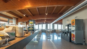 Una cocina amplia con vigas de madera, una encimera larga con diversos alimentos y un refrigerador con dispensador de bebidas.