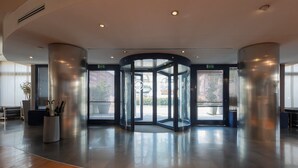 Un vestíbulo moderno con puerta giratoria, ventanas amplias y suelo de madera.