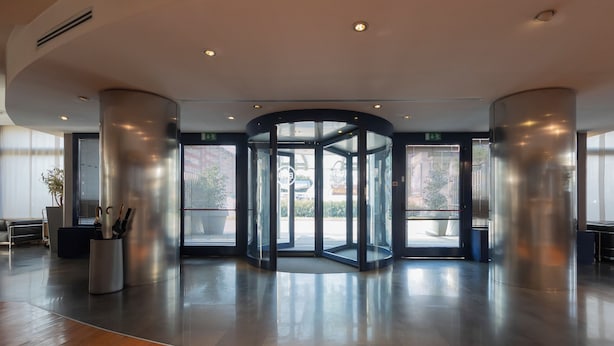 Un hall d’entrée moderne doté d’une porte tournante, de grandes fenêtres et d’un plancher en bois.