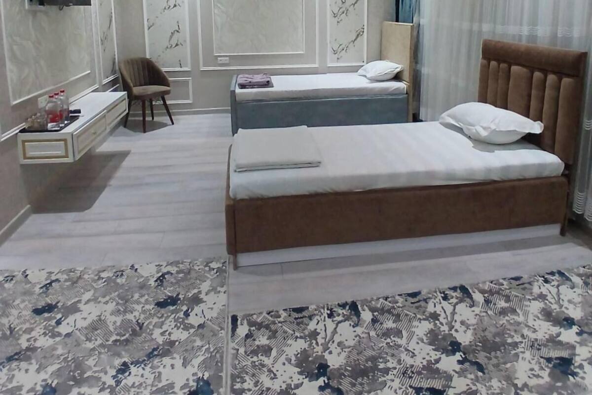 Un dormitorio moderno con una cama grande, una mesita de noche, una silla y un televisor instalado en la pared.