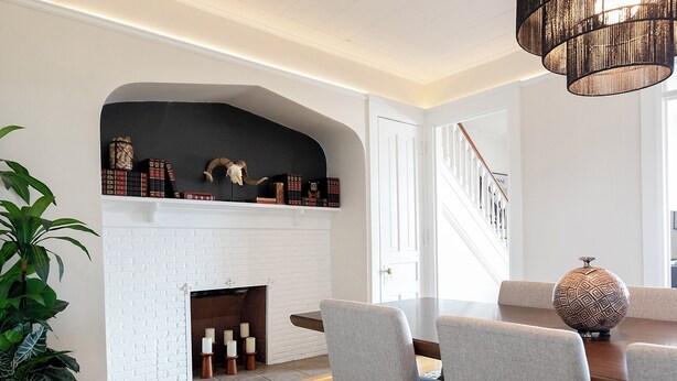 A dining area with a white brick fireplace, bookshelves, and a staircase. - Charming 1901 Home, Modern Updates, Near Lake Superior (Duluth)