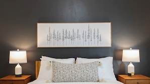 A neatly made bed with two bedside lamps, a patterned throw pillow, and a framed artwork above. - Charming 1901 Home, Modern Updates, Near Lake Superior (Duluth)