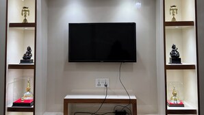 Un'elegante parete attrezzata moderna con televisore a schermo piatto, scaffali in legno e vetrine che espongono oggetti decorativi.