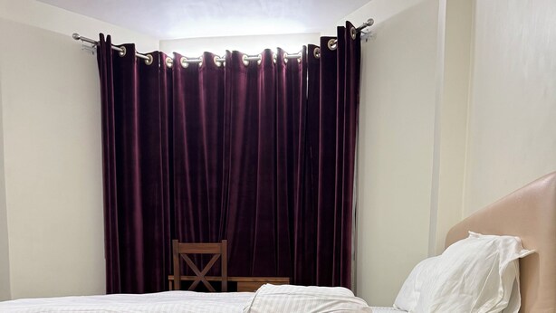 Una camera da letto con un letto, un comodino, una sedia e una finestra con tende.