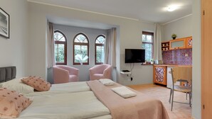A bedroom with two beds, a TV, a small kitchenette, and a chair. - Zacisze Centrum 2 9 12byGrand Apartments (Sopot)