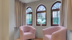 A room with three arched windows, a light-colored floor, and two pink chairs. - Zacisze Centrum 2 9 12byGrand Apartments (Sopot)
