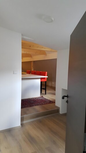 A modern interior with a wooden ceiling, a white table with red chairs, and a patterned rug. - Apartment 'Neue Wunderschöne' with Shared Terrace and Wi-Fi (Rockenhausen)