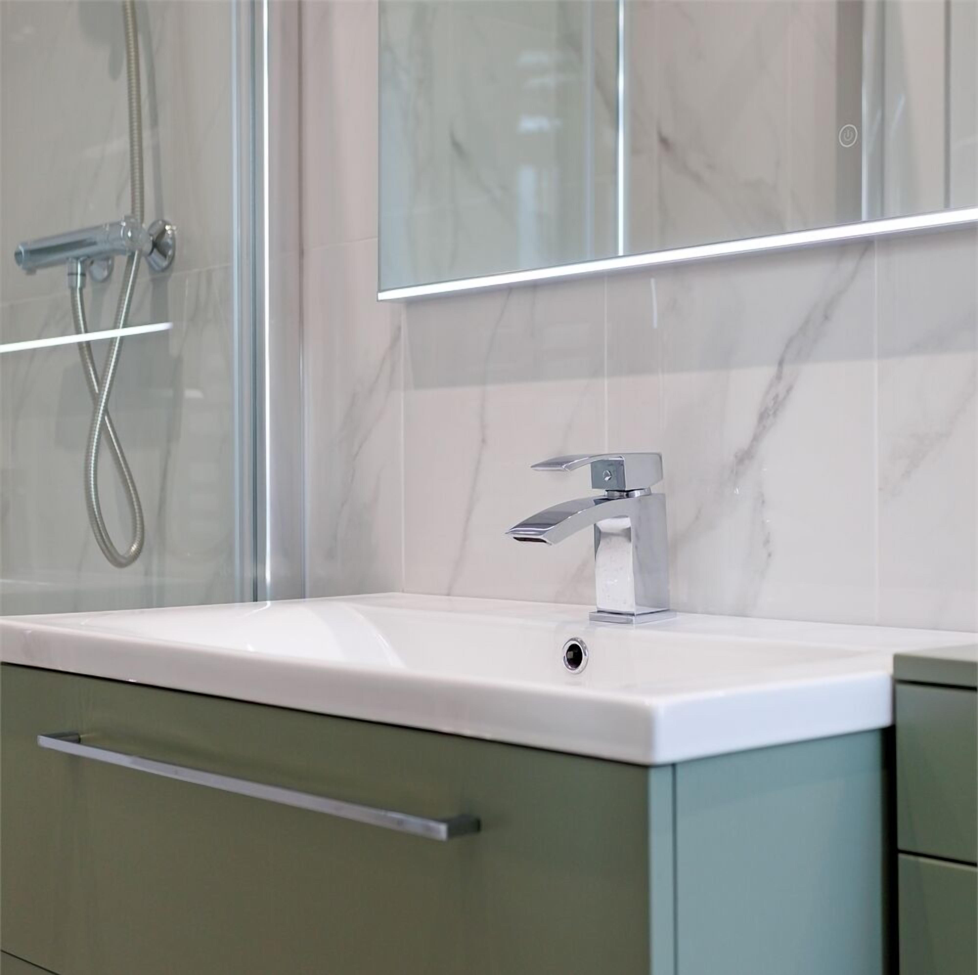 Luxe tweepersoonskamer | Badkamer | Een douche, een haardroger, handdoeken, zeep