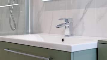 Luxe tweepersoonskamer | Badkamer | Een douche, een haardroger, handdoeken, zeep