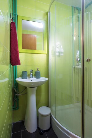 A bathroom with a sink, mirror, and shower enclosure.