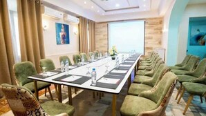 A conference room with a long table, green upholstered chairs, and a projector screen. - Suisse Hotel - Alger Centre (Algiers)