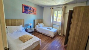 A room with two single beds, wooden headboards, a nightstand with a lamp, a radiator, and a window with curtains. - Suisse Hotel - Alger Centre (Algiers)
