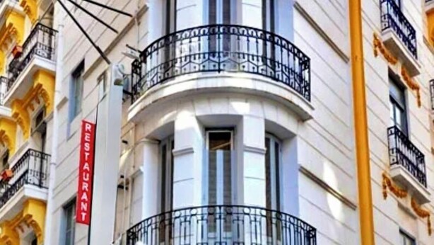 A building with a curved entrance, a sign reading "Suisse," and a red cross symbol. - Suisse Hotel - Alger Centre (Algiers)