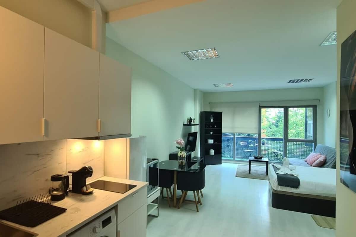A modern apartment with a kitchen, dining area, and a balcony with a view.