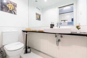 Un baño moderno con inodoro, lavamanos y espejo.