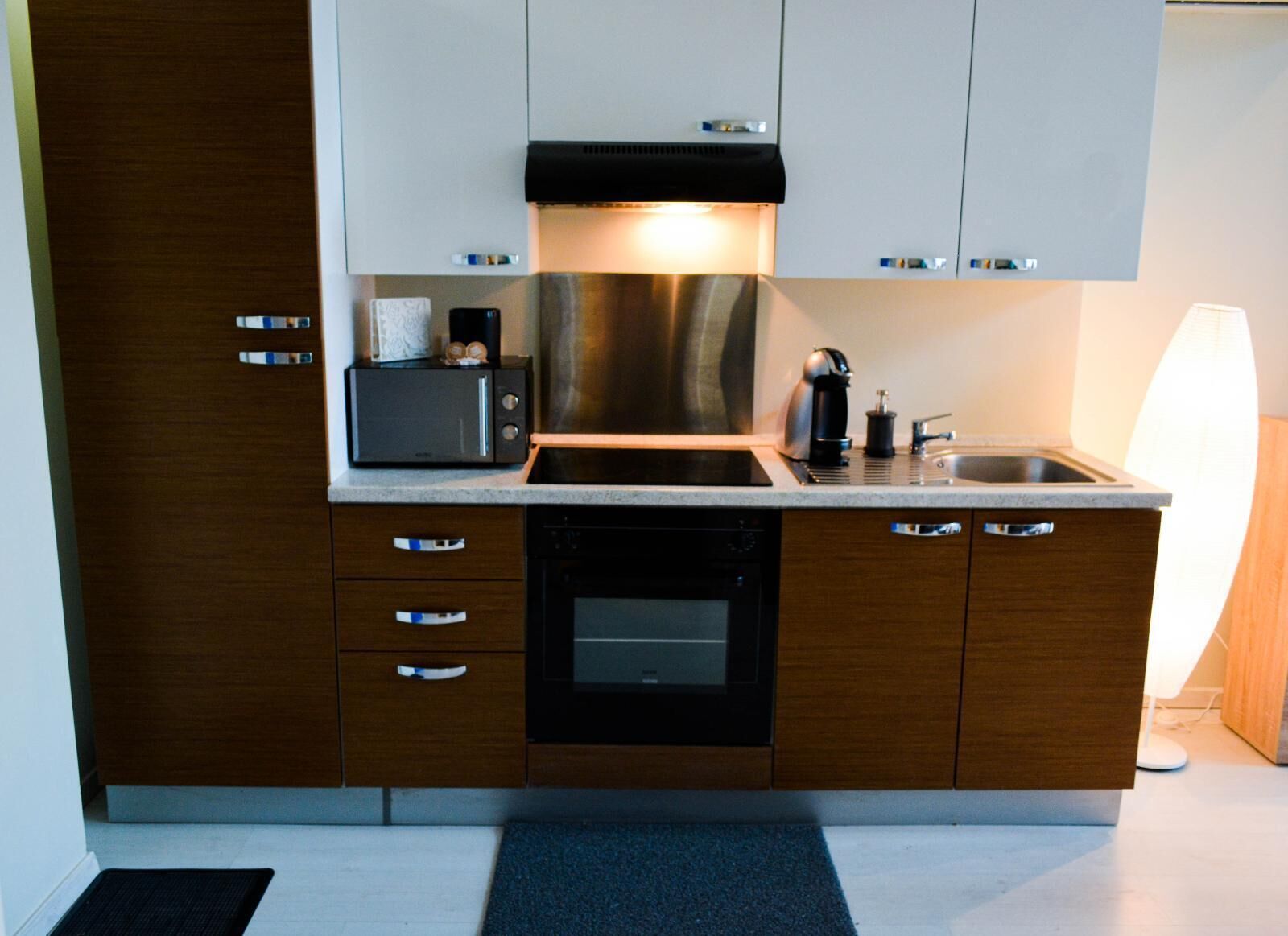 A modern kitchen with wooden cabinets, a stainless steel range hood, a microwave, a coffee maker, and a dishwasher.
