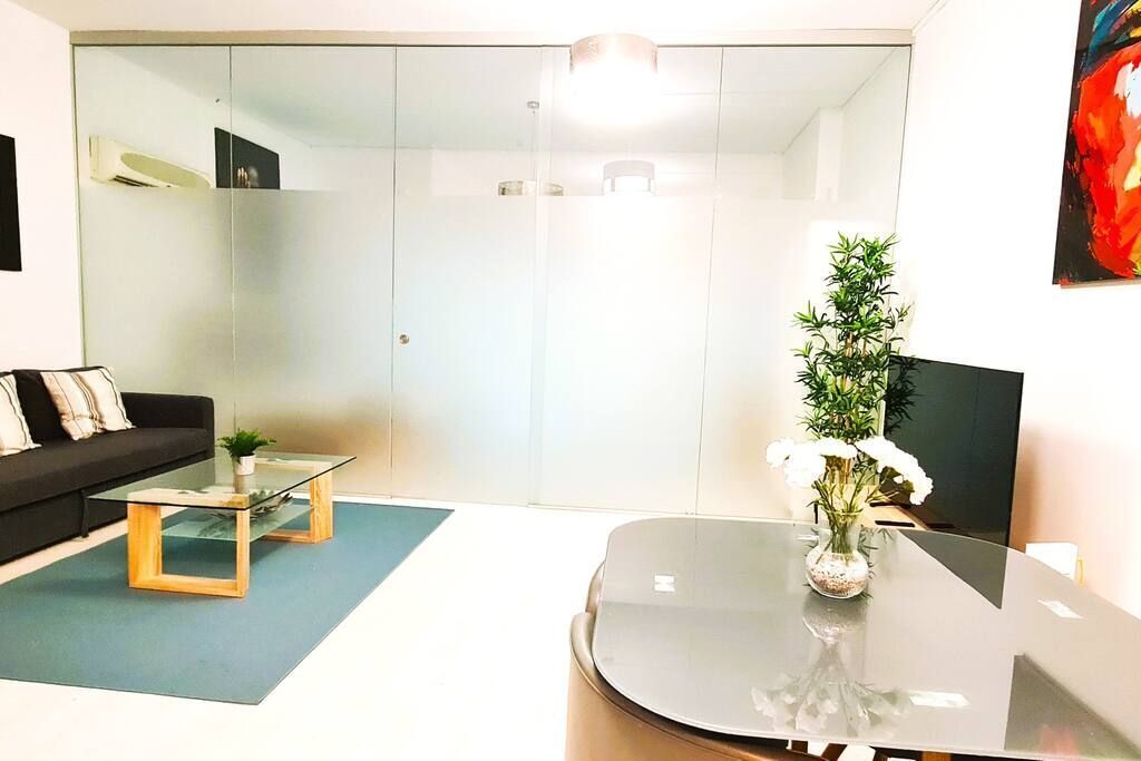 Una sala de estar moderna con una mesa de centro de vidrio, un sofá y una planta en maceta.