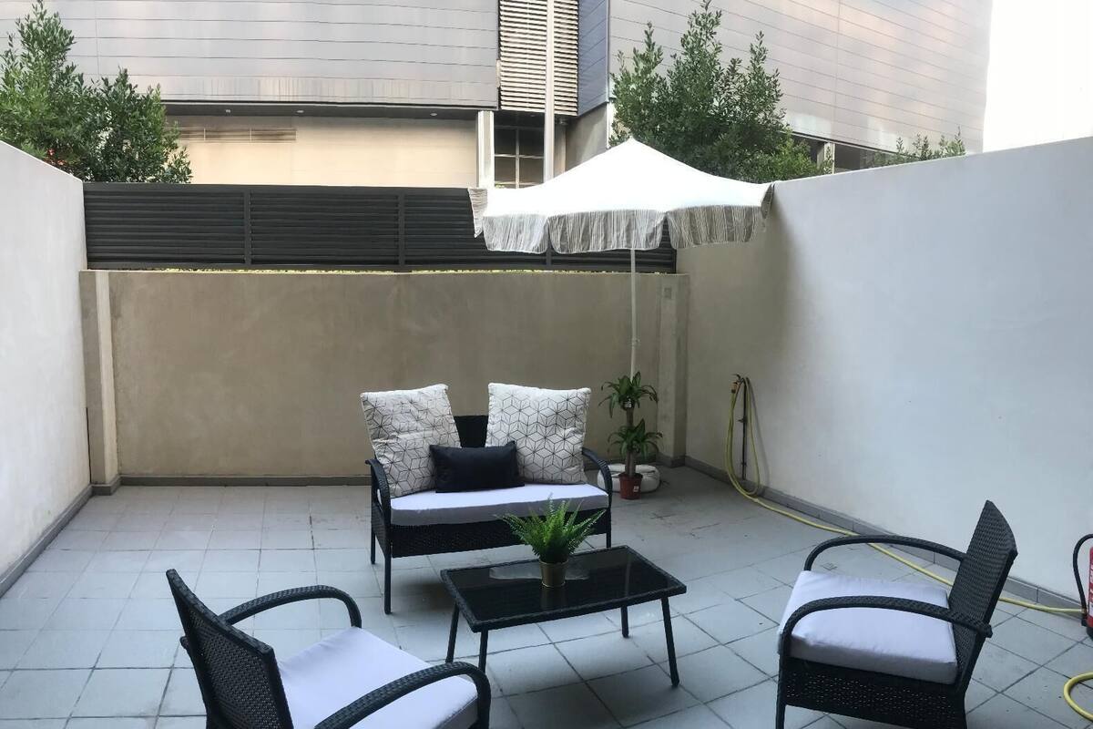 A patio with a sofa set, two chairs, a coffee table, and a potted plant.
