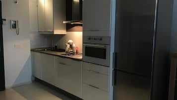 Superior appartement | Privékeuken | Een koelkast met diepvriezer, een microgolfoven, een kookplaat